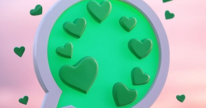 Mano sosteniendo un teléfono con mensaje romántico en pantalla y corazón dibujado en fondo borroso