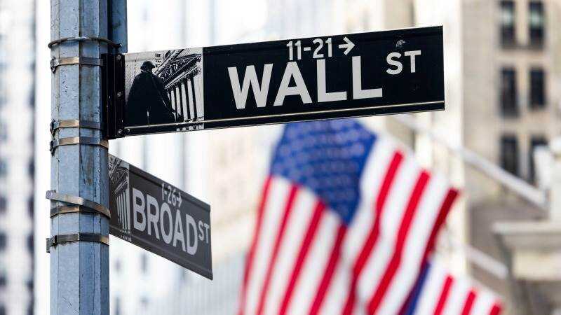Kevin Warsh en rueda de prensa como nuevo presidente de la Fed con gráficos de inflación al 3.5% y caídas en Wall Street de fondo