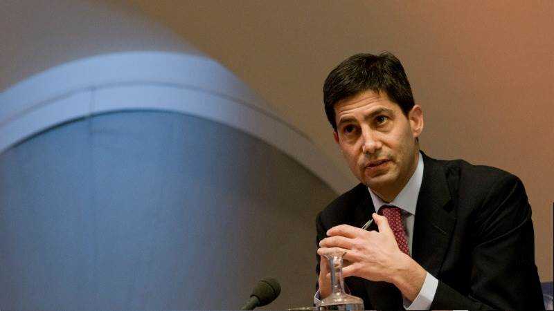 Kevin Warsh en rueda de prensa como nuevo presidente de la Fed con gráficos de inflación y tipos de interés al fondo