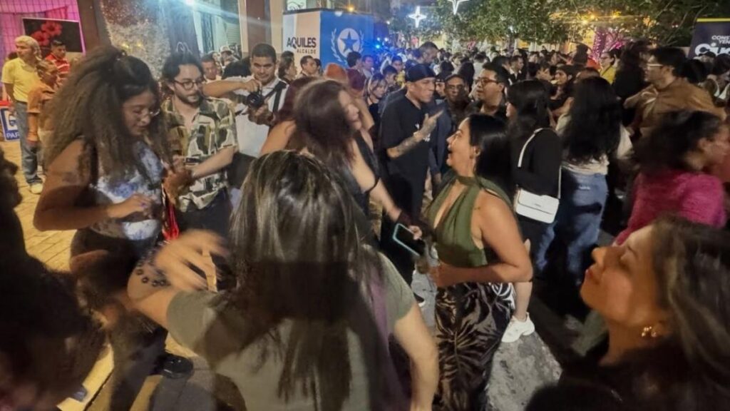Multitud bailando en la calle Panamá de Guayaquil durante 'Baila la calle 2026', con murales coloniales y luces nocturnas de fondo