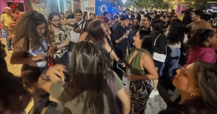 Multitud bailando en la calle Panamá de Guayaquil durante 'Baila la calle 2026', con murales coloniales y luces nocturnas de fondo
