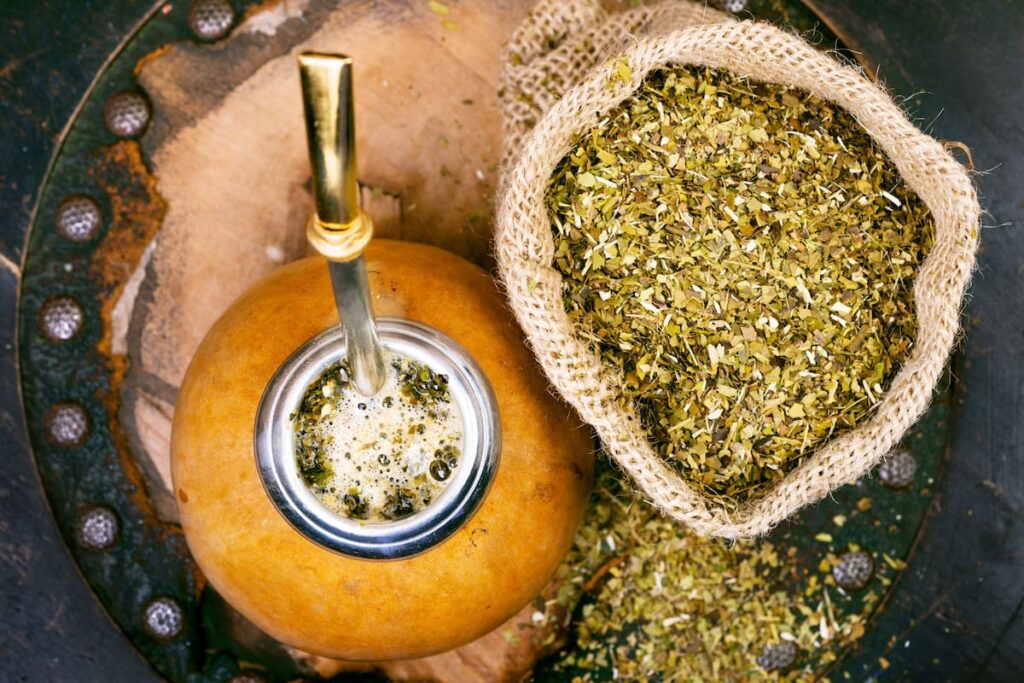 Científicos analizan yerba mate usada transformada en bioaceite oscuro y granulado de biochar en laboratorio, con equipo de pirólisis al fondo