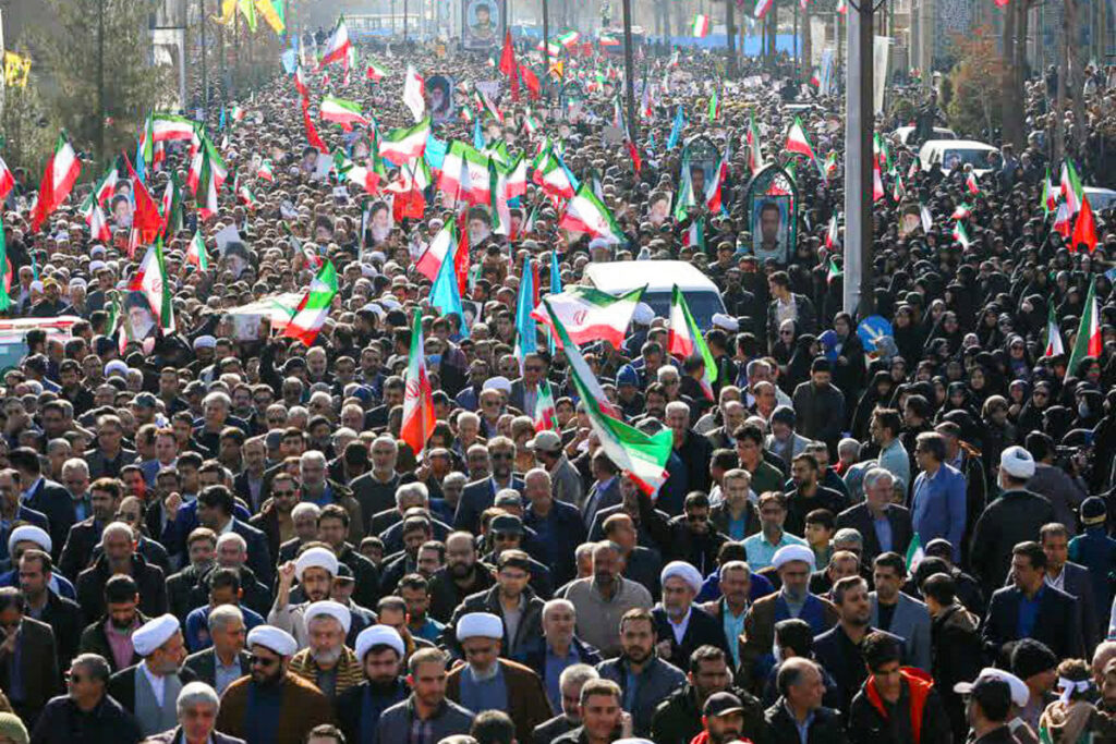 Multitud progobierno en Kerman (Irán, enero 2026) con banderas y carteles mientras crece tensión por posibles bombardeos de EEUU