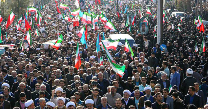 Multitud progobierno en Kerman (Irán, enero 2026) con banderas y carteles mientras crece tensión por posibles bombardeos de EEUU