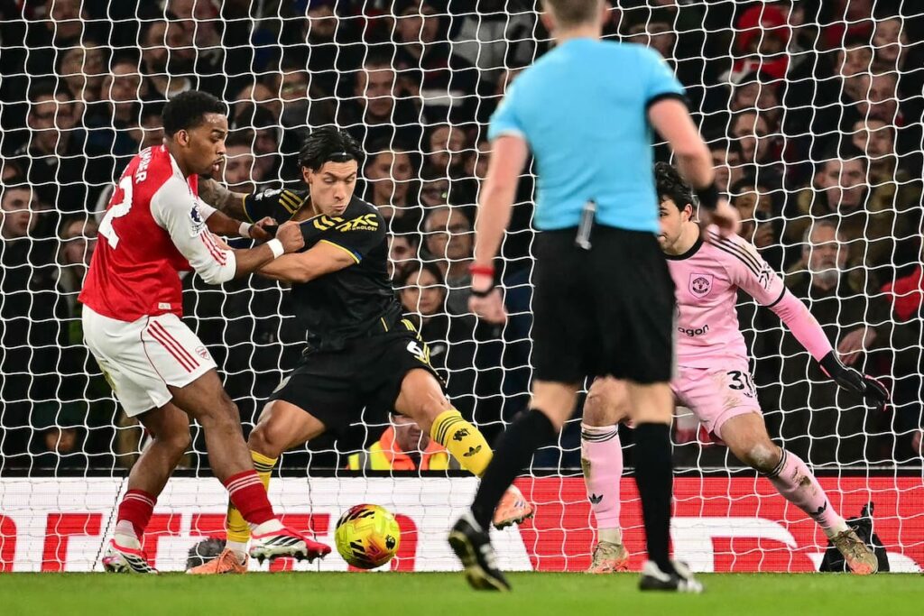 Lisandro Martínez con gesto de dolor tras su gol en contra, mientras Cunha celebra el 3-2 al Arsenal en el Emirates