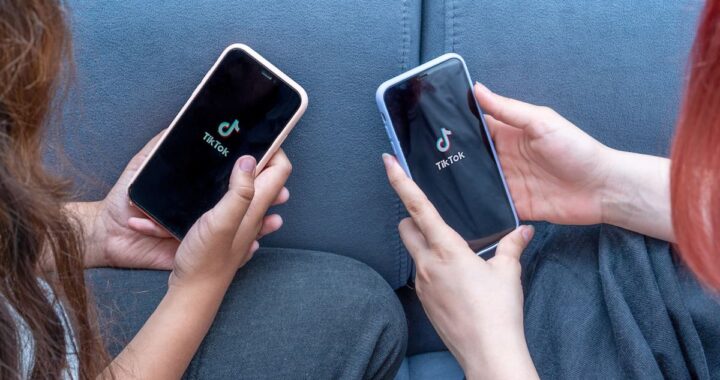 Adolescente usando TikTok en la oscuridad, con luz azul reflejada en su rostro y reloj marcando las 23:45