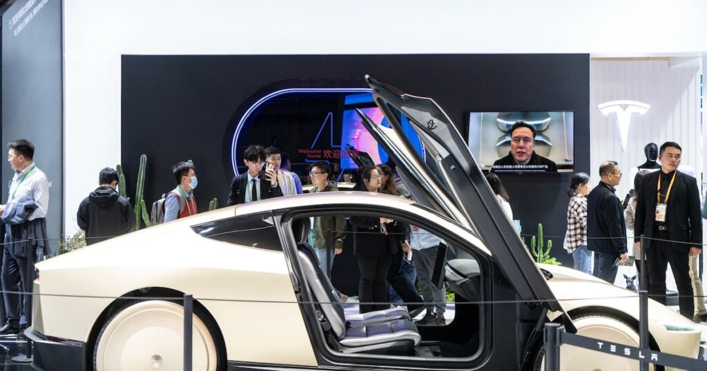Jensen Huang (Nvidia) y Elon Musk (Tesla) en pantalla dividida durante el CES 2026 con gráficos de IA para coches autónomos