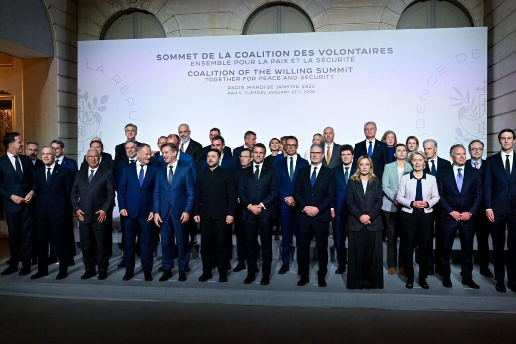 Bandera de Ucrania junto a documentos firmados por 35 países en mesa de negociaciones en París con mapa estratégico de Europa del Este