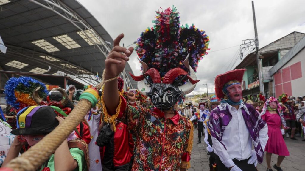 Diablos con máscaras artesanales de 11 kg bailando en la Diablada de Píllaro, Ecuador
