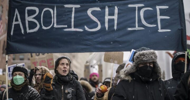 Protestas en Minneapolis por Alex Pretti con carteles exigiendo justicia y bandera de la UE difuminada al fondo