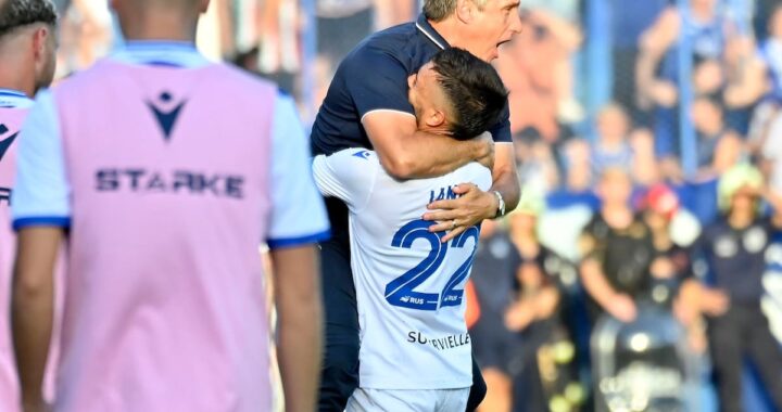 Carlos Tevez de espaldas a Guillermo Barros Schelotto en el banco de Vélez, con mirada tensa y el campo de Liniers al fondo