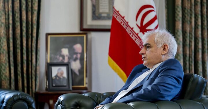 Embajador iraní en entrevista tensa con mapa de Oriente Medio y bandera de Irán al fondo