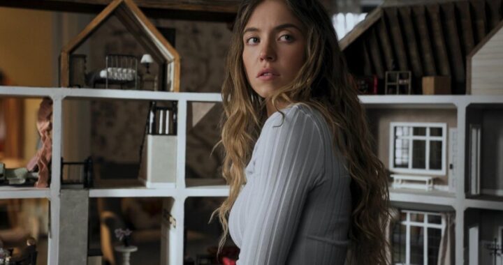 Sydney Sweeney en escena icónica de 'The Housemaid' con vestido rojo y mirada fatal, simbolizando el regreso del thriller erótico