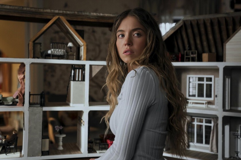 Sydney Sweeney en escena icónica de 'The Housemaid' con vestido rojo y mirada fatal, simbolizando el regreso del thriller erótico