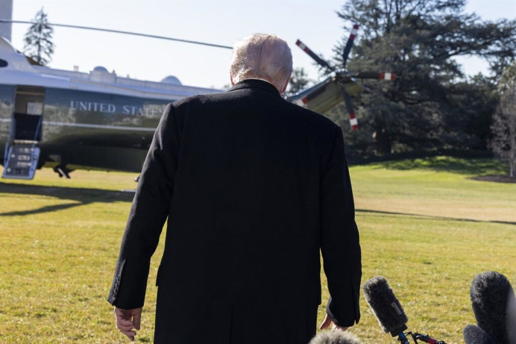 Donald Trump firmando documentos oficiales en el Despacho Oval con banderas de EE.UU. y el sello presidencial, simbolizando sus 225 órdenes ejecutivas de 2025