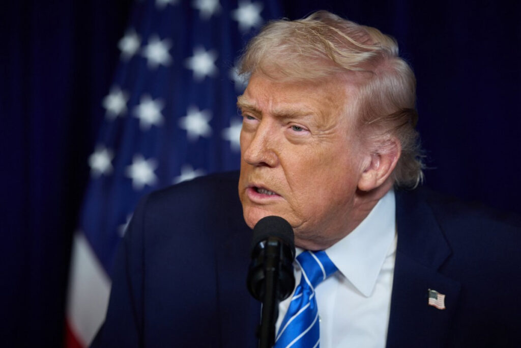 Donald Trump en rueda de prensa señalando a Delcy Rodríguez con mapa de Venezuela y barriles de petróleo de fondo
