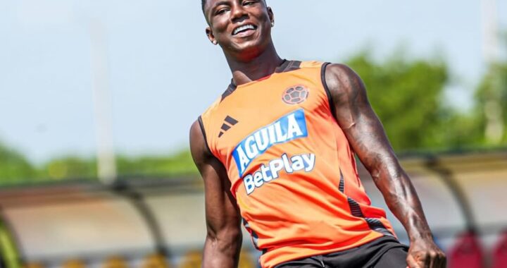 Marino Hinestroza con camiseta de Boca Juniors tras firmar por US$5M, sonriendo con fondo de La Bombonera y el barrio Olaya Herrera en contraste
