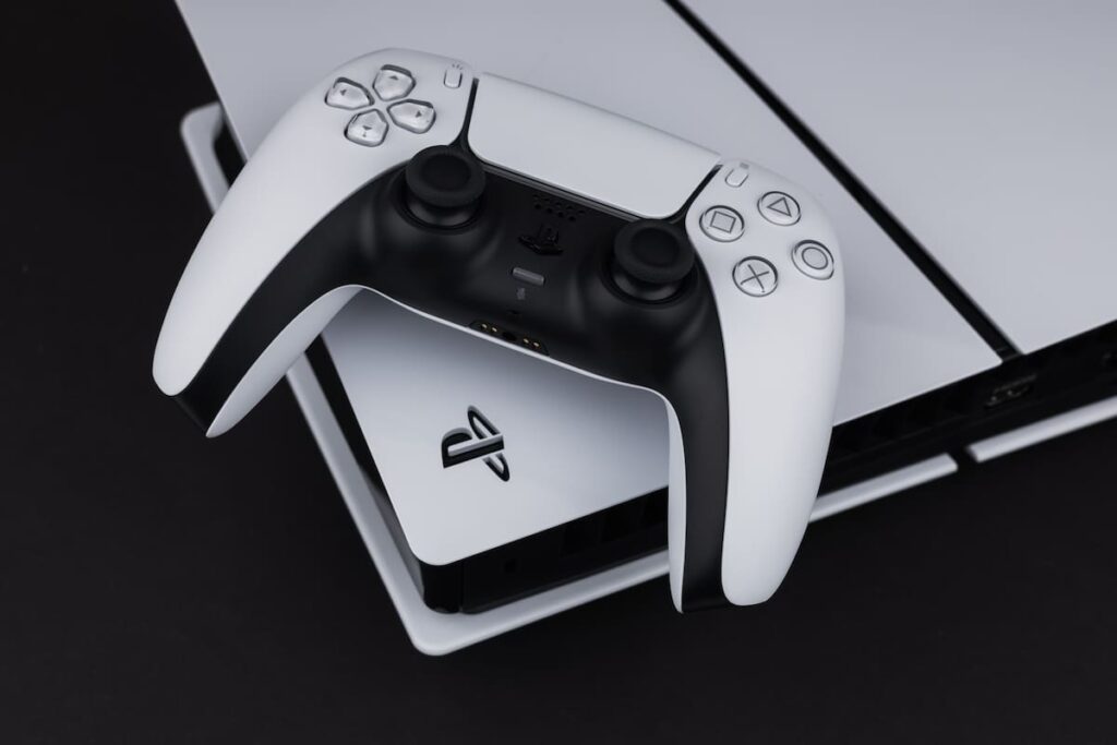 Consola PS5 con gráficos de ventas en caída libre y fondo de juegos exclusivos como 'Spider-Man 2'