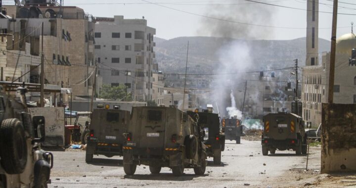 Manifestantes palestinos en Jericó durante operación militar israelí con soldados armados al fondo