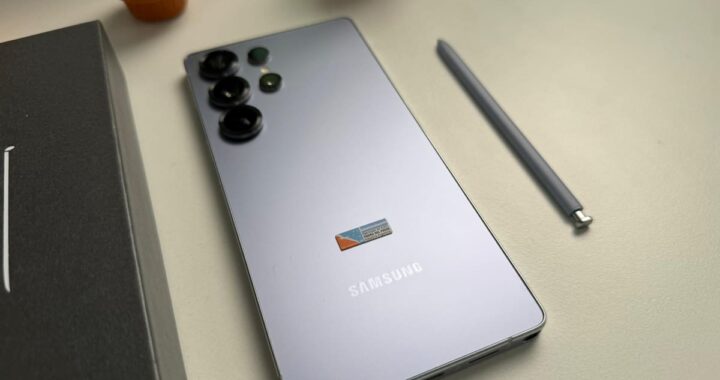 Prototipo del Samsung Galaxy S26 mostrando su pantalla con interfaz de IA y logo de Galaxy Unpacked 2025