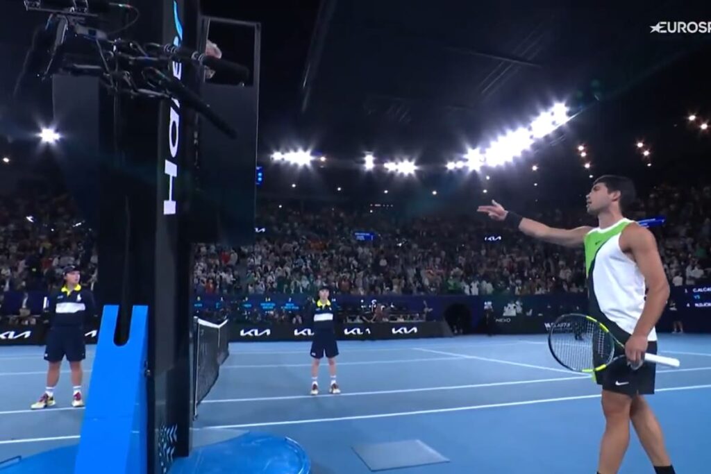 Carlos Alcaraz protesta al juez por el techo cerrado en la final del Australian Open 2026 contra Djokovic, con el serbio al fondo celebrando un punto