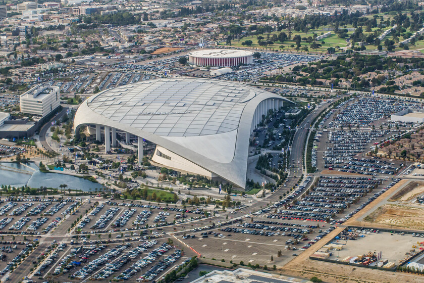 Fila de coches frente a estadio del Mundial 2026 con cartel de 'Parking: $300' destacando el coste récord