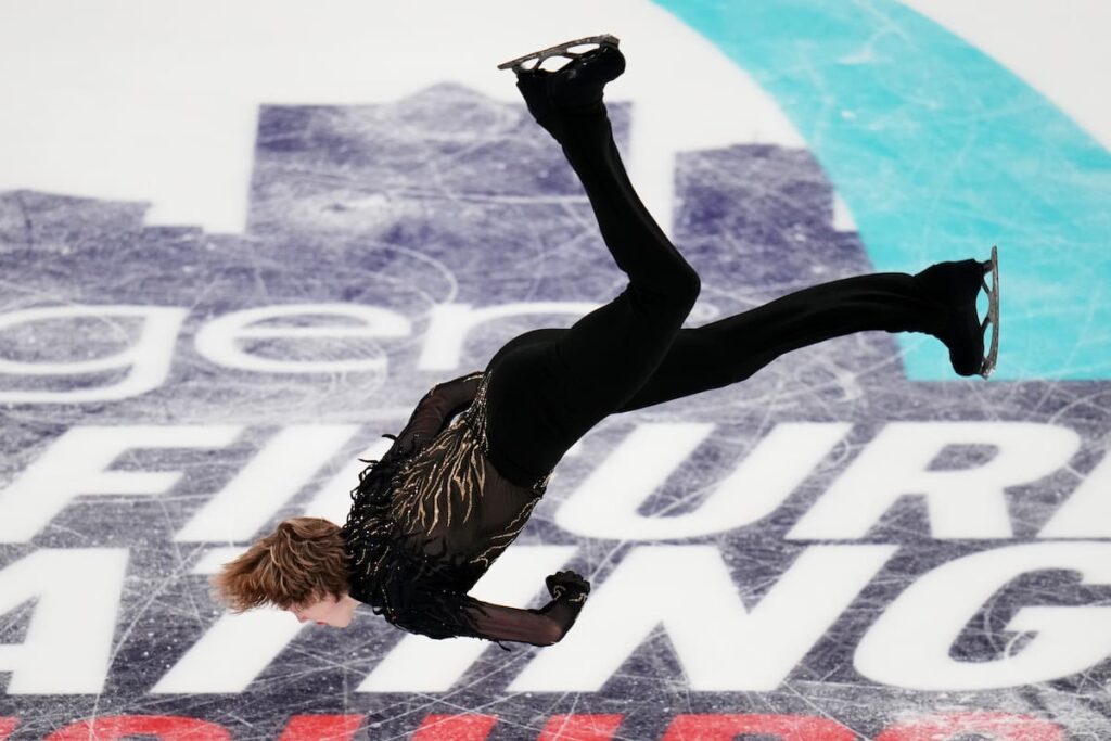 Ilia Malinin en pleno backflip sobre hielo durante rutina olímpica 2026 con público en vilo