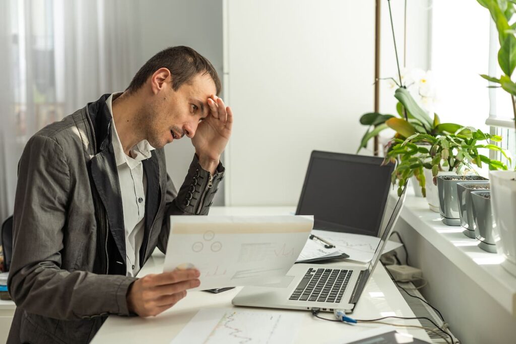 Empleado agotado frente a pantalla con gráficos de IA y datos de productividad en aumento