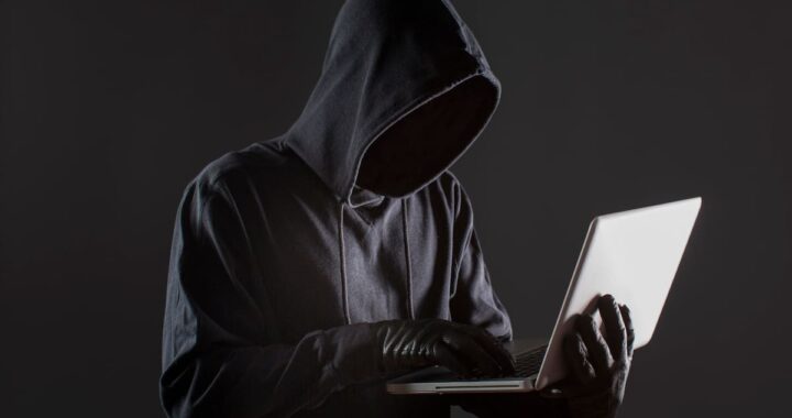 Pantalla de computadora con alerta roja de 'Acceso no autorizado detectado' y código malicioso en segundo plano