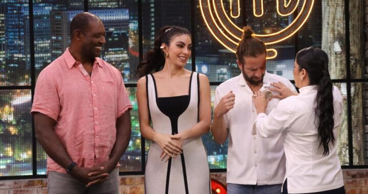 Bastián Napolitano sostiene el pin del chef en MasterChef con expresión decidida frente a Beber Espinoza