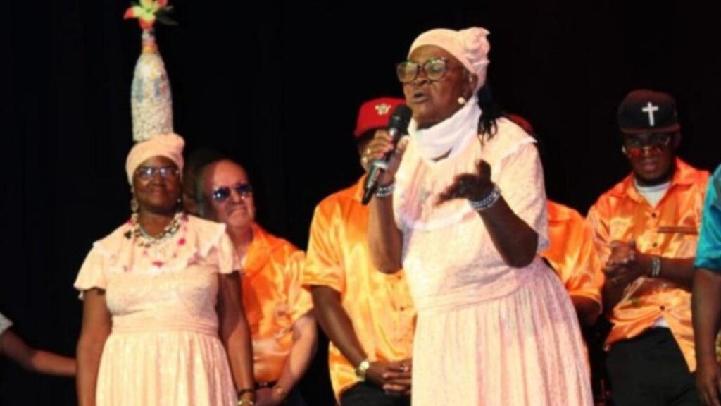 Retrato de Gloria Pavón, leyenda de la Bomba del Chota, con micrófono y expresión de pasión en escena
