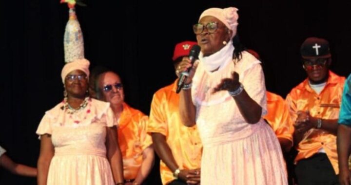 Retrato de Gloria Pavón, leyenda de la Bomba del Chota, con micrófono y expresión de pasión en escena
