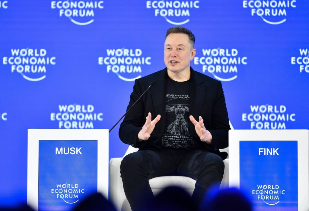 Elon Musk en Davos anunciando que la IA superará la inteligencia humana en 5 años con robots como Optimus de Tesla