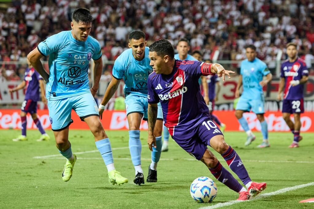 Jugadores de River en el Estadio Hernando Siles de La Paz con cielo nublado y montaña al fondo