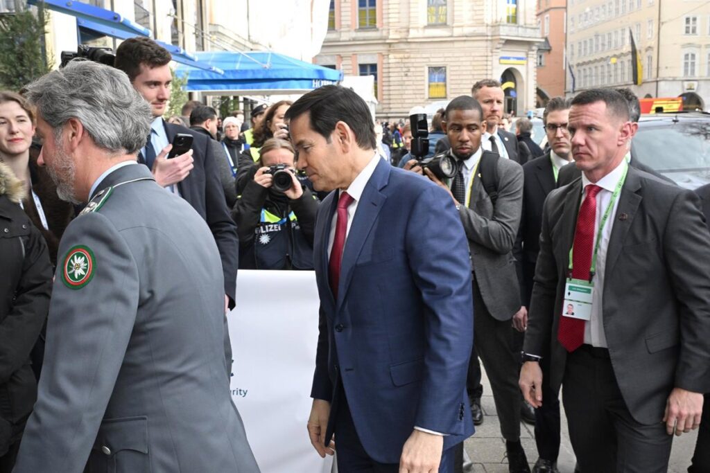 Marco Rubio en conferencia con bandera de EEUU y UE al fondo, tensión diplomática visible en gestos