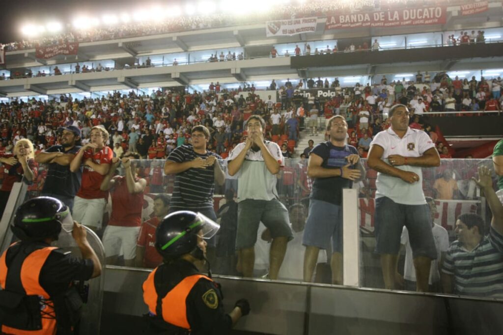 Hincha con el rostro tenso gritando 'movete y dejá de joder' desde la tribuna en un estadio argentino lleno de tensión