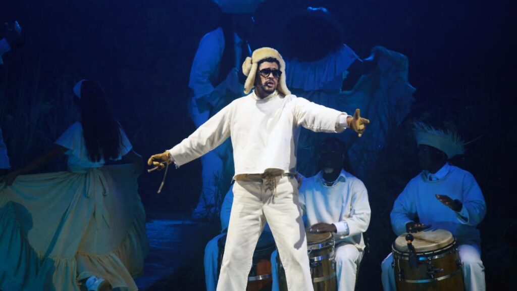 Bad Bunny en el escenario del Super Bowl LX con micrófono y luces de fondo, desafiando con su música