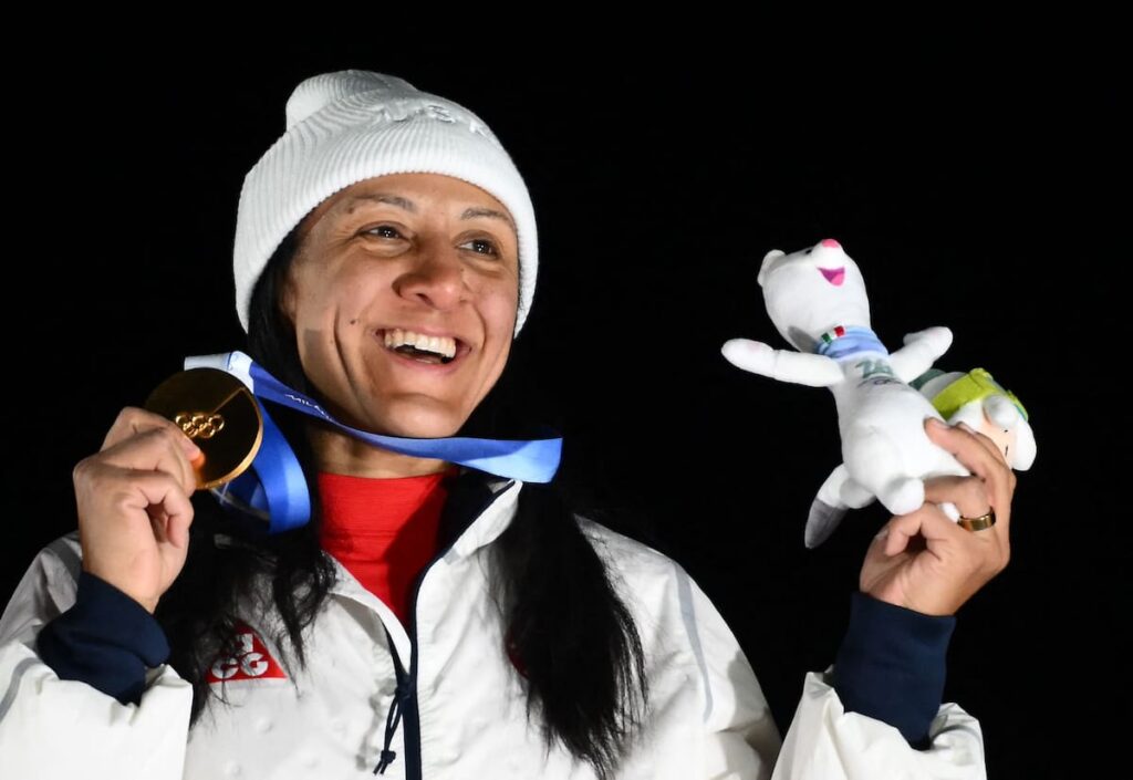 Elana Meyers Taylor con medalla de oro en bobsleigh, abrazando a sus hijos sordos en el podio olímpico