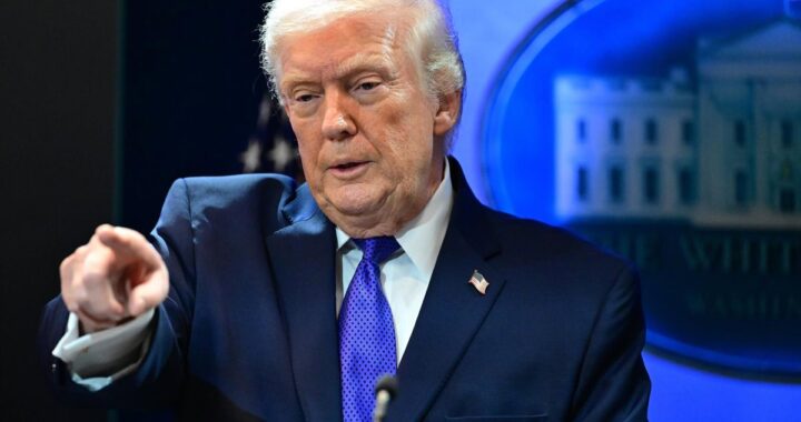 Donald Trump firma documento con gráficos de aranceles al 15% y caída de bolsa en pantallas de fondo