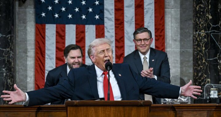 Donald Trump señalando con gesto airado durante discurso en el Congreso, con cartel de protesta 'Las personas negras no son simios' al fondo