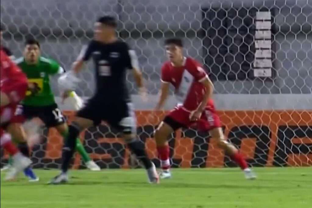 Jugador de Riestra celebra el gol de caño mientras el rival reclama un penal no cobrado en el área