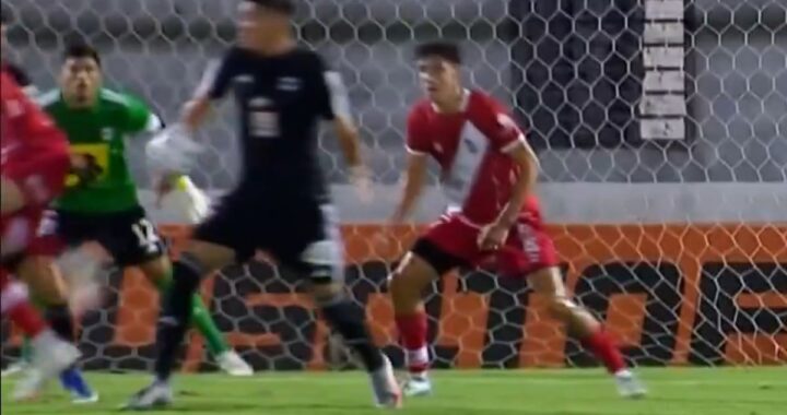 Jugador de Riestra celebra el gol de caño mientras el rival reclama un penal no cobrado en el área
