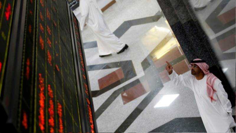 Pantallas rojas en la bolsa de Dubái mostrando 'Mercado cerrado' con gráficos de caída de petróleo y dirham en segundo plano