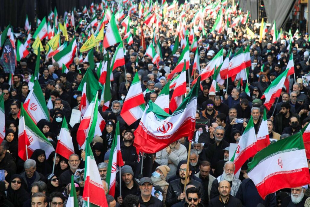 Bandera de Irán ondeando frente a mapa del estrecho de Ormuz con petroleros en segundo plano