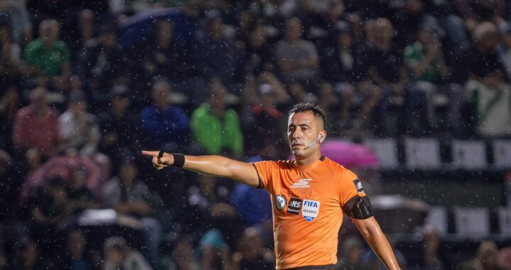 Árbitro Lobo Medina muestra tarjeta roja a jugador de Banfield bajo lluvia intensa y mirada de hinchas