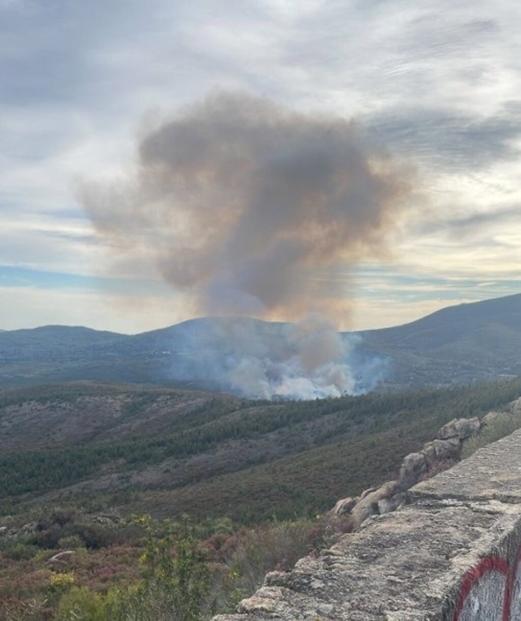 Bomberos forestales y helicóptero combaten incendio en Sierra de Gata con humo denso al fondo