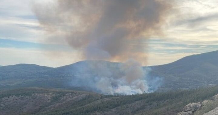 Bomberos forestales y helicóptero combaten incendio en Sierra de Gata con humo denso al fondo