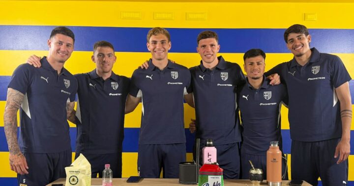 Grupo de 6 futbolistas argentinos de Parma sonriendo con camisetas del club y mate en mano en el estadio Tardini