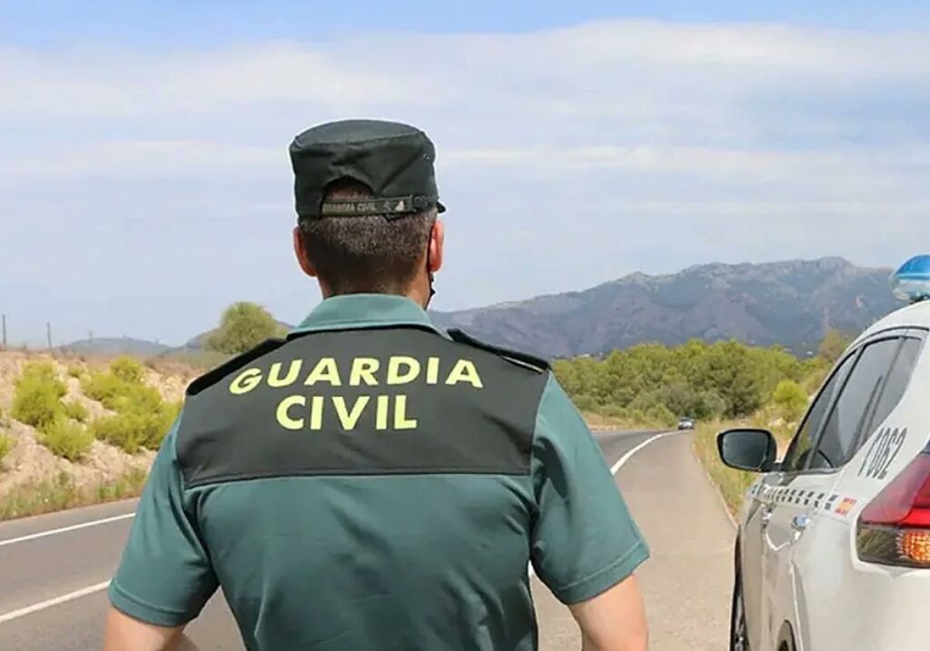 Agentes de la Guardia Civil practicando RCP a un conductor en el arcén de la N-2, con helicóptero medicalizado aterrizando al fondo