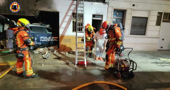 Fachada de vivienda destruida tras impacto de coche policial con humo y bomberos trabajando en Alaquàs